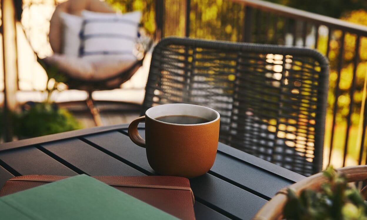cup of coffee and books on a table on patio